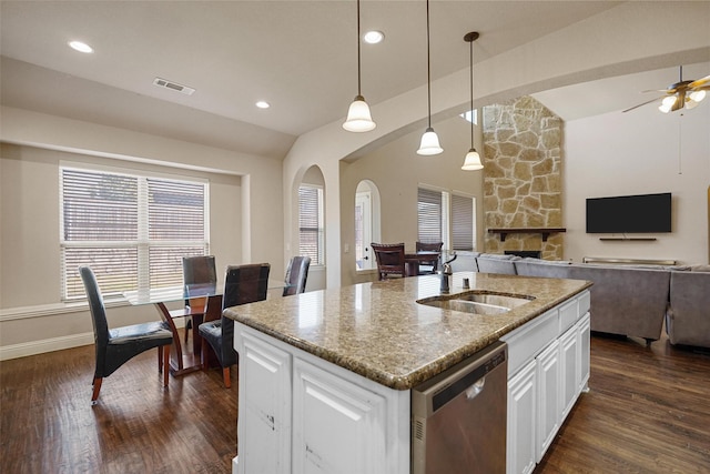 kitchen featuring visible vents, light stone countertops, dark wood-style flooring, stainless steel dishwasher, and a sink