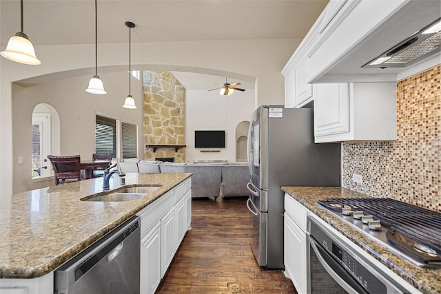 kitchen with a sink, dark wood-style floors, arched walkways, appliances with stainless steel finishes, and custom exhaust hood