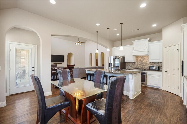 dining room with visible vents, a ceiling fan, dark wood-style floors, arched walkways, and lofted ceiling