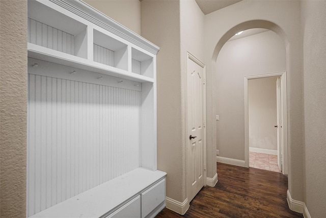 mudroom with arched walkways, dark wood-style flooring, and baseboards