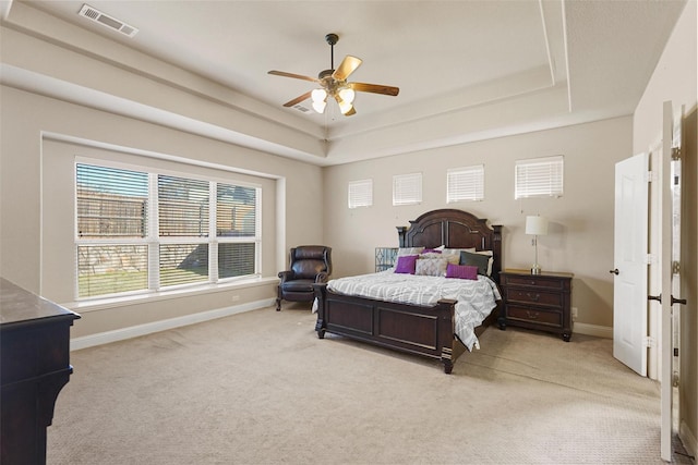 bedroom with light carpet, visible vents, and a raised ceiling