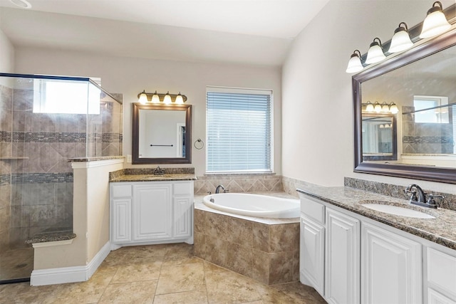 bathroom featuring a bath, two vanities, walk in shower, and a sink