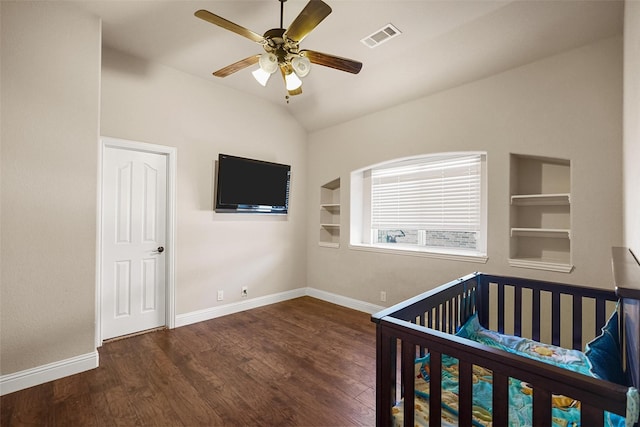 unfurnished bedroom featuring visible vents, baseboards, lofted ceiling, wood finished floors, and a nursery area