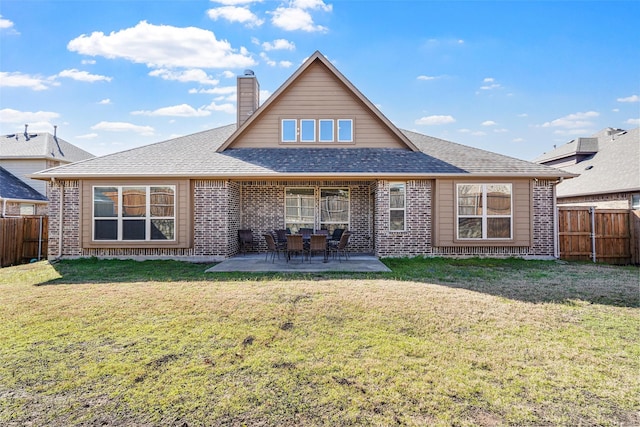 back of house with brick siding, a yard, and a fenced backyard