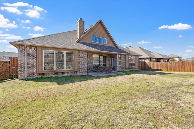 rear view of house with brick siding, a fenced backyard, a lawn, and a patio area