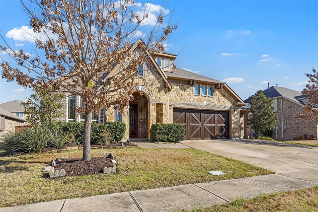 view of front of house featuring stone siding, a front yard, and driveway