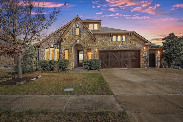 view of front of home with stone siding, an attached garage, driveway, and a front lawn