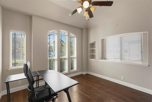 home office featuring built in shelves, baseboards, dark wood-style floors, and ceiling fan