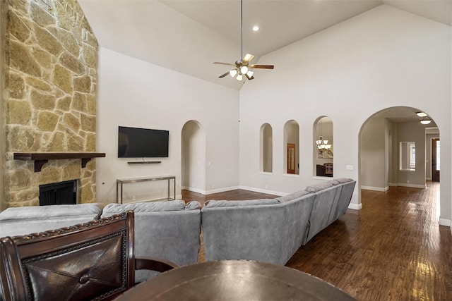 living area with wood finished floors, a fireplace, arched walkways, and high vaulted ceiling