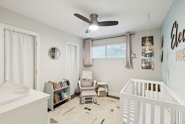 bedroom with baseboards, a crib, and ceiling fan