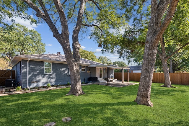 rear view of house with brick siding, a fenced backyard, and a patio area