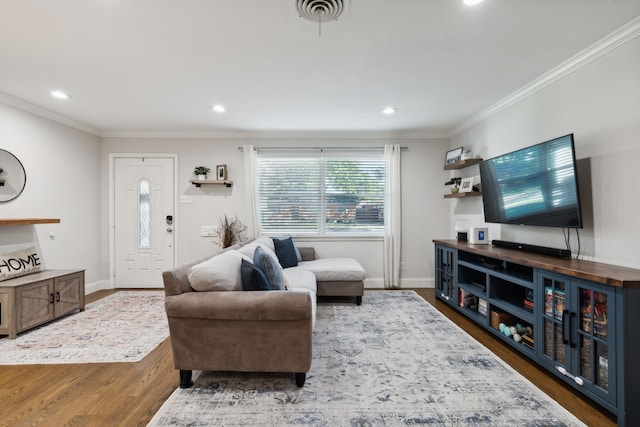 living room featuring visible vents, baseboards, wood finished floors, and ornamental molding