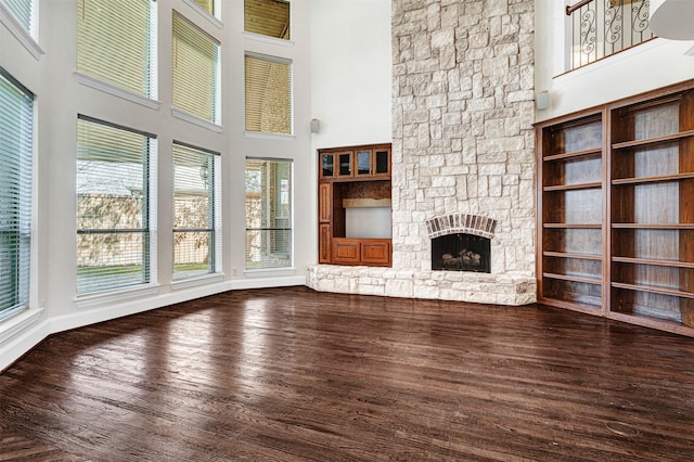 2521 Alexa Ct, Plano, TX 75075 - unfurnished living room with a towering ceiling, dark wood-type flooring, a stone fireplace, and baseboards