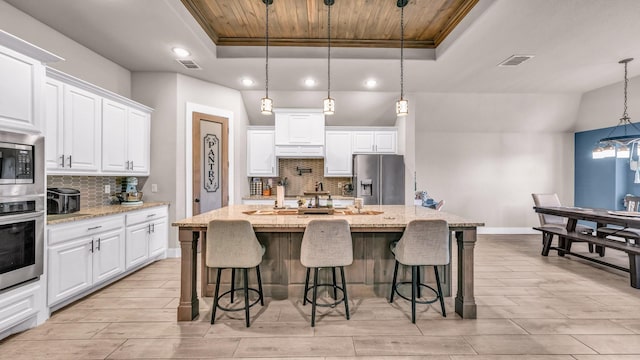 kitchen featuring a tray ceiling, stainless steel appliances, visible vents, and wood ceiling