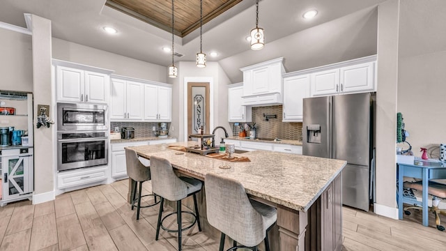 kitchen with wine cooler, a breakfast bar area, a tray ceiling, appliances with stainless steel finishes, and a sink