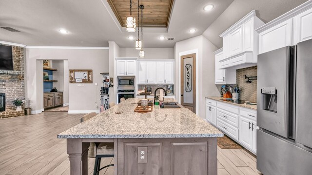 kitchen with visible vents, a tray ceiling, a sink, appliances with stainless steel finishes, and a brick fireplace