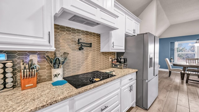 kitchen with premium range hood, stainless steel fridge with ice dispenser, white cabinetry, black electric stovetop, and backsplash