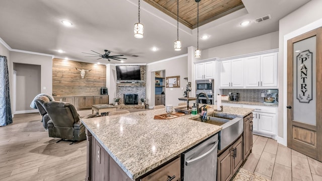 kitchen featuring a fireplace, a sink, decorative backsplash, stainless steel appliances, and crown molding