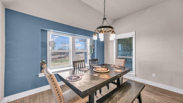 dining space featuring baseboards, lofted ceiling, and wood finished floors