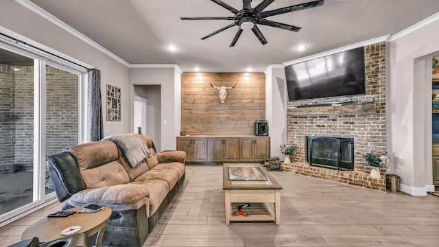 living room with light wood-type flooring, a ceiling fan, recessed lighting, a fireplace, and crown molding