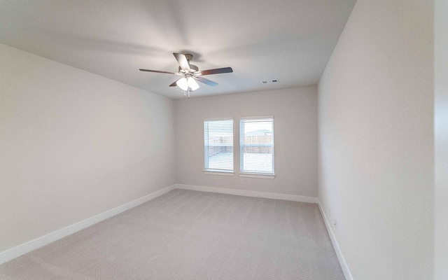 empty room featuring baseboards, light carpet, visible vents, and a ceiling fan