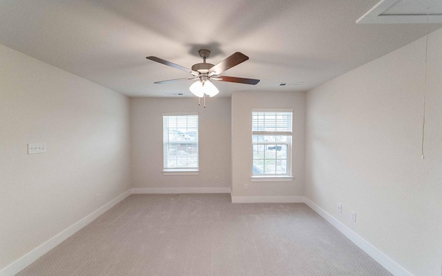 empty room with baseboards, light carpet, attic access, and a ceiling fan