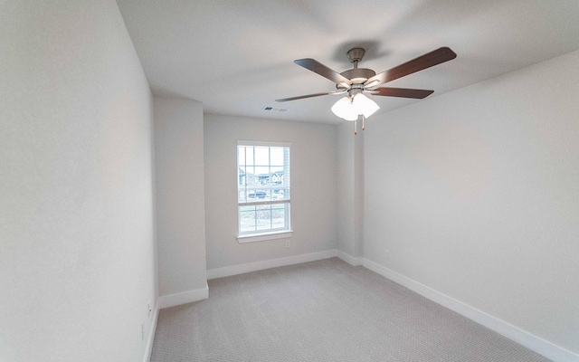 spare room with a ceiling fan, baseboards, visible vents, and light carpet