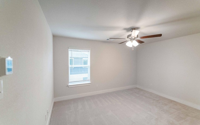 spare room with baseboards, light carpet, and a ceiling fan