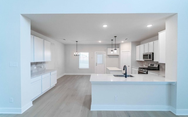 kitchen featuring white cabinetry, a peninsula, stainless steel appliances, and a sink