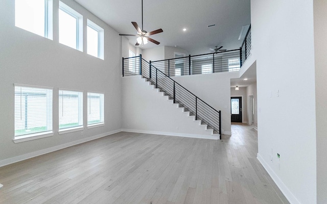 unfurnished living room featuring light wood finished floors, stairway, and baseboards