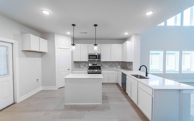 kitchen featuring visible vents, a sink, tasteful backsplash, stainless steel appliances, and a peninsula