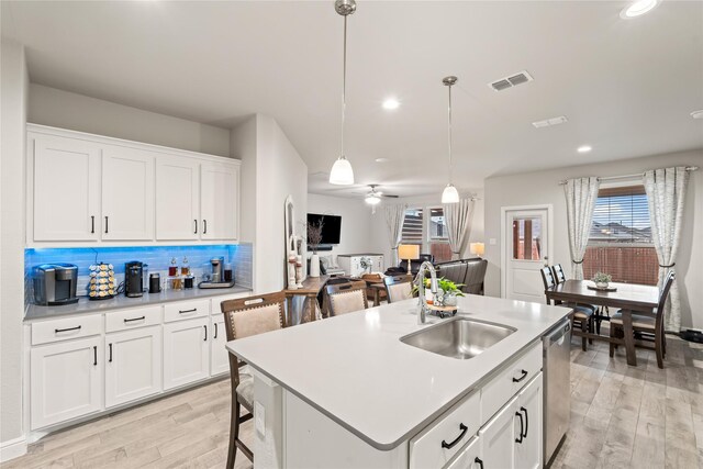 kitchen with visible vents, backsplash, dishwasher, light wood-style floors, and a sink