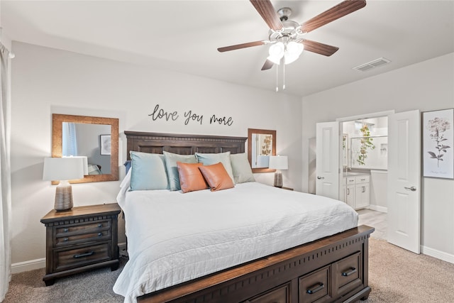 bedroom featuring ensuite bath, light colored carpet, visible vents, and baseboards