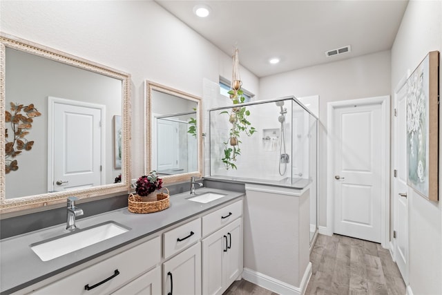 full bath with a stall shower, wood finished floors, visible vents, and a sink