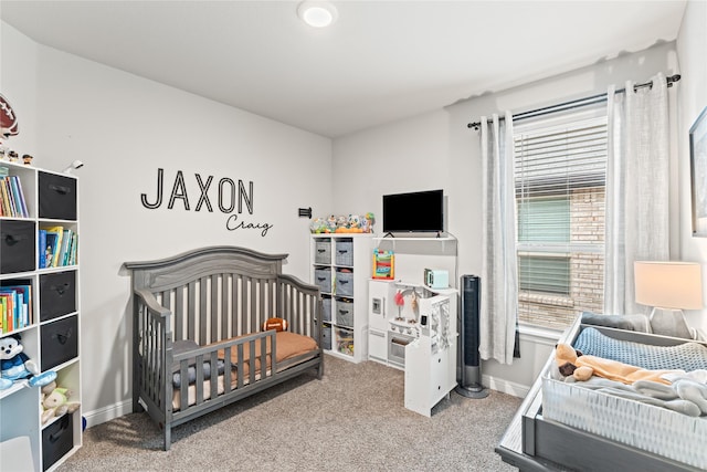 bedroom with a crib, baseboards, and carpet