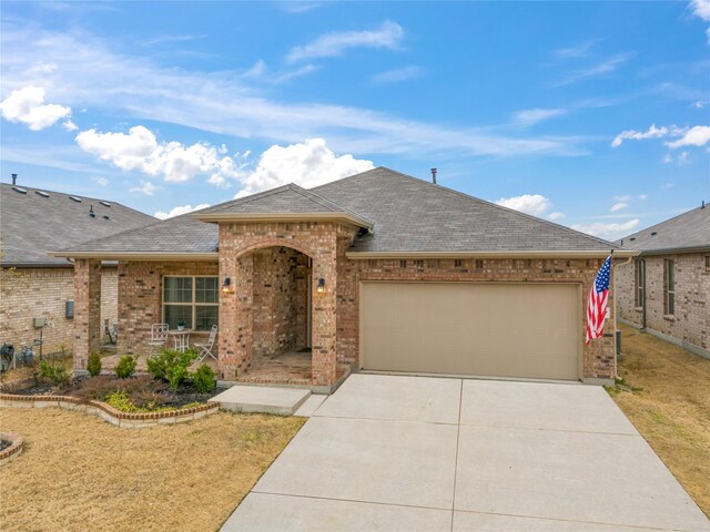 view of front of property featuring brick siding, an attached garage, driveway, and a shingled roof