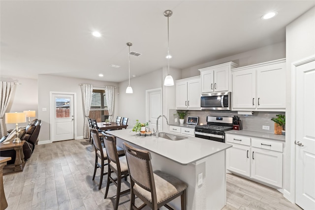 kitchen featuring visible vents, backsplash, light wood-style floors, stainless steel appliances, and a sink