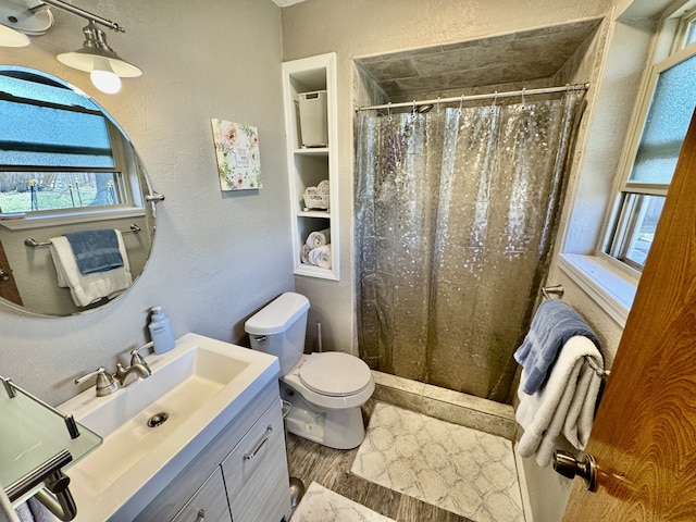 full bath with toilet, a stall shower, vanity, and a textured wall