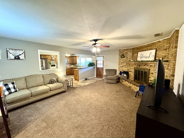 living area with visible vents, light carpet, a ceiling fan, a textured ceiling, and a brick fireplace