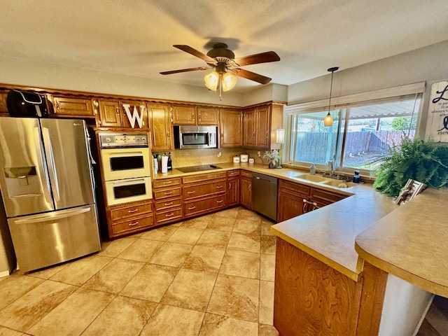 kitchen featuring brown cabinetry, stainless steel appliances, light countertops, and a sink