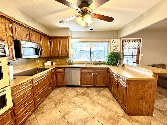 kitchen with a sink, stainless steel appliances, brown cabinets, and a peninsula