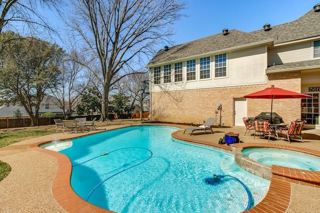 view of pool with fence, a pool with connected hot tub, and a patio area