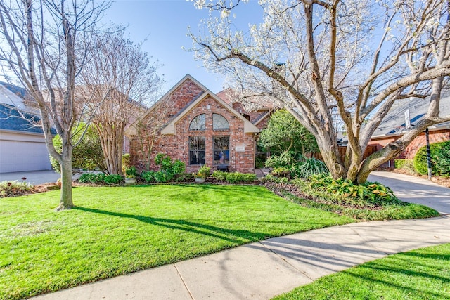 view of front facade with a front lawn, brick siding, and driveway