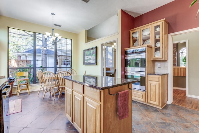 kitchen with tasteful backsplash, a center island, stainless steel double oven, glass insert cabinets, and a chandelier