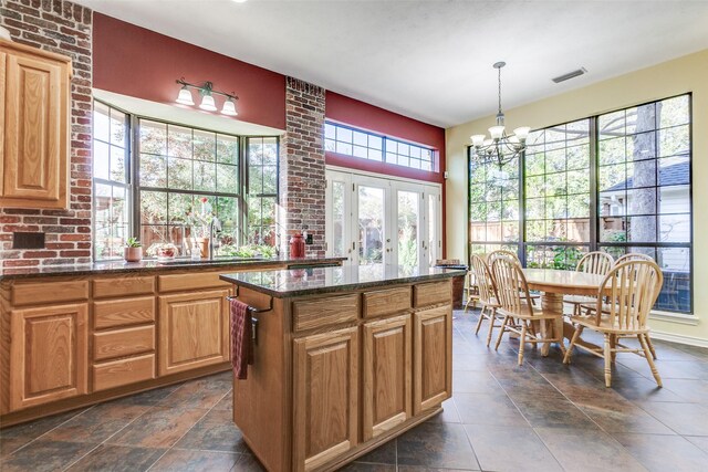 kitchen featuring a sink, decorative light fixtures, french doors, dark stone counters, and an inviting chandelier