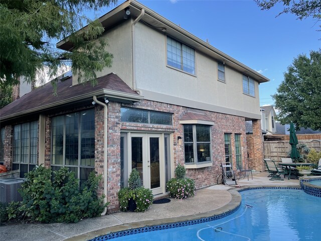 rear view of house featuring brick siding, fence, stucco siding, french doors, and a patio