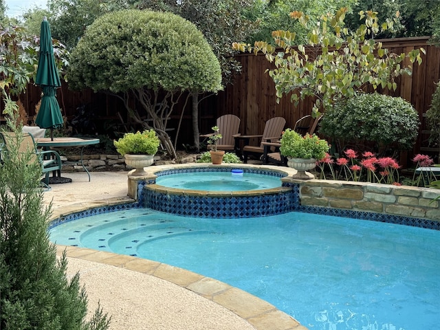 view of pool featuring a patio area, a pool with connected hot tub, and a fenced backyard