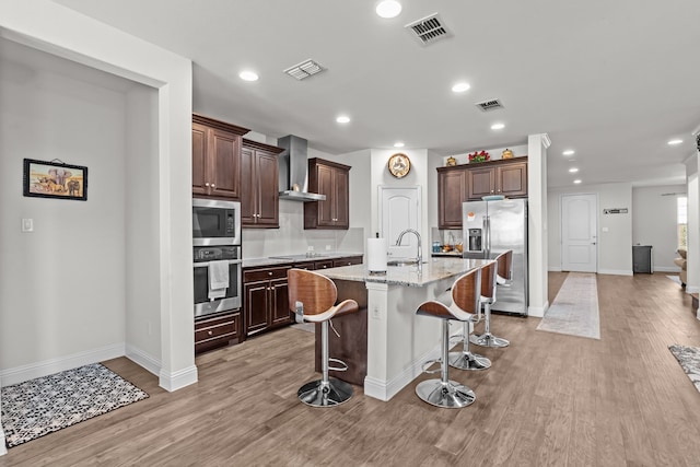 kitchen featuring wall chimney exhaust hood, visible vents, and appliances with stainless steel finishes