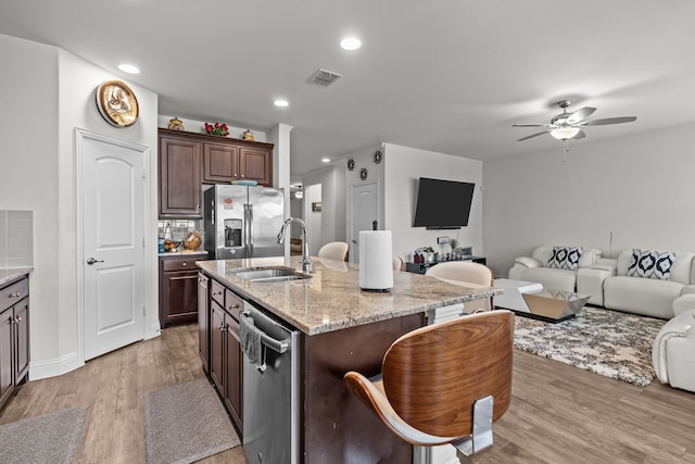 kitchen featuring visible vents, a sink, open floor plan, stainless steel appliances, and light wood-style floors