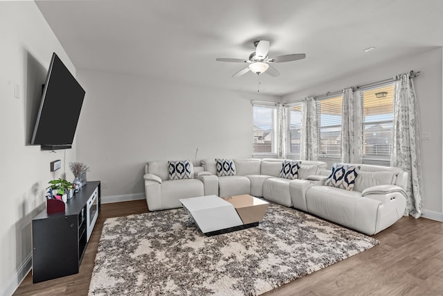 living room with a ceiling fan, baseboards, and wood finished floors